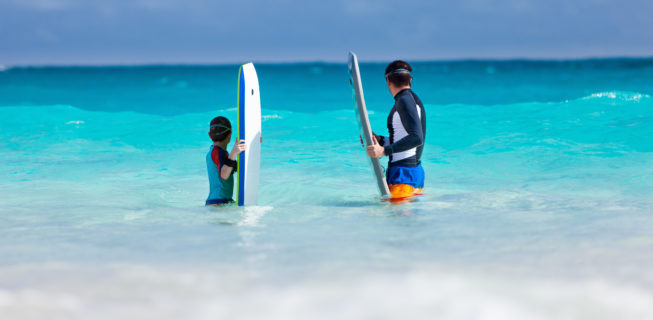father and son bodyboarding and waiting for a wave